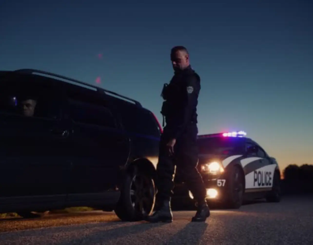 A police officer standing next to his car.